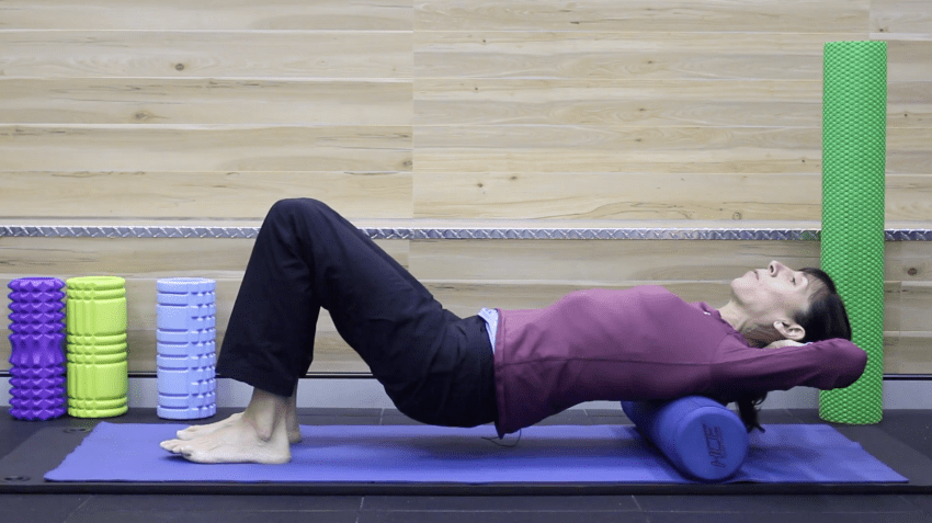 A person finds relief by using a high-density foam roller for lower back pain on a yoga mat.