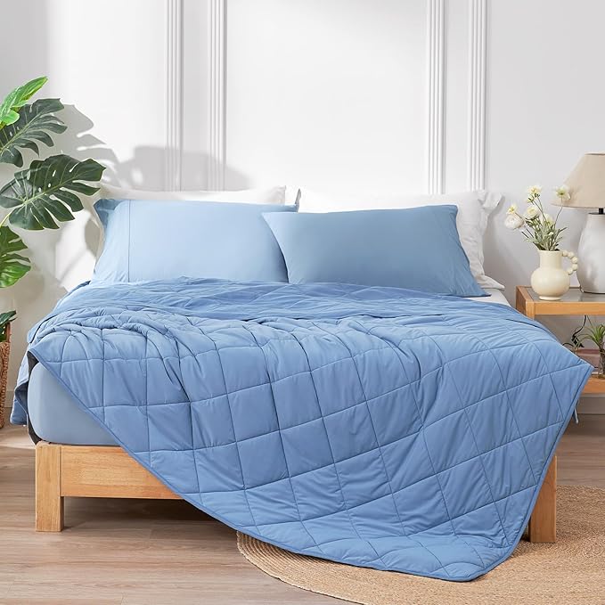 A folded grey weighted blanket for anxiety resting on a bed, showcasing its quilted texture for even pressure distribution.