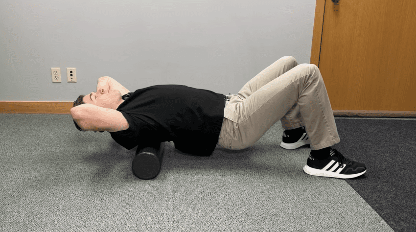 A person finds relief using a high-density foam roller for a bad back on a yoga mat.
