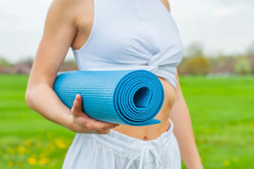 A person unrolling the best yoga mat on a wooden floor before starting their practice.