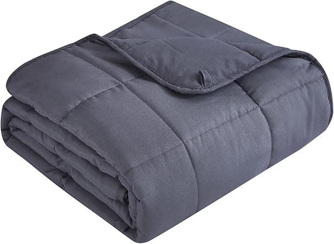 A folded grey weighted blanket for anxiety resting on a bed, showcasing its quilted texture for even pressure distribution.